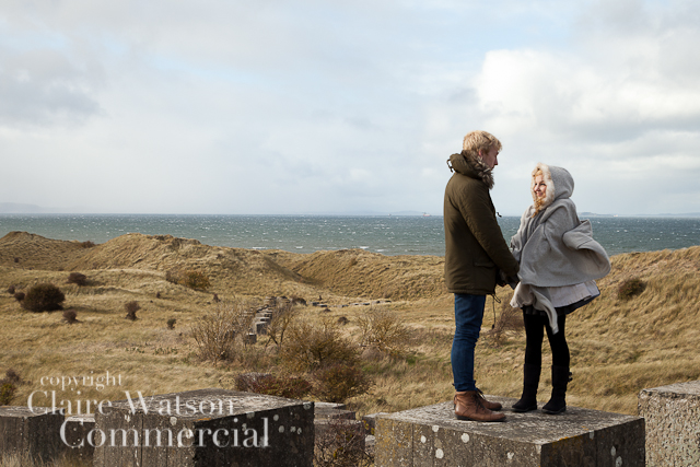 couple standing on a concrete pillar at Gullane